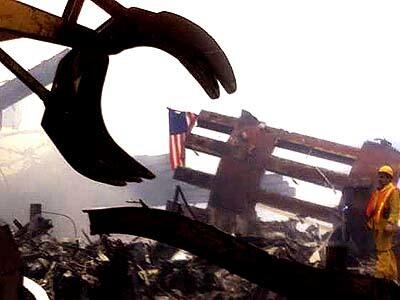 A steam shovel removes the larger pieces of rubble.