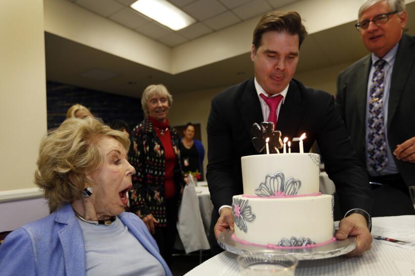 Anne Douglas, left, shows her surprise as Ivan Klassen and Herb Smith of the Los Angeles Mission deliver a cake at her birthday lunch at the mission's Anne Douglas Center for Women.