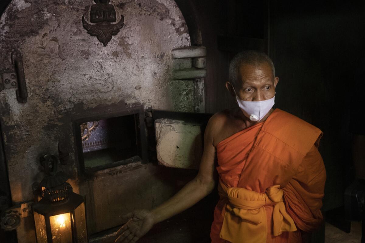 A Buddhist monk fields media questions  after putting the coffin of the infamous Si Ouey into an incinerator for cremation.