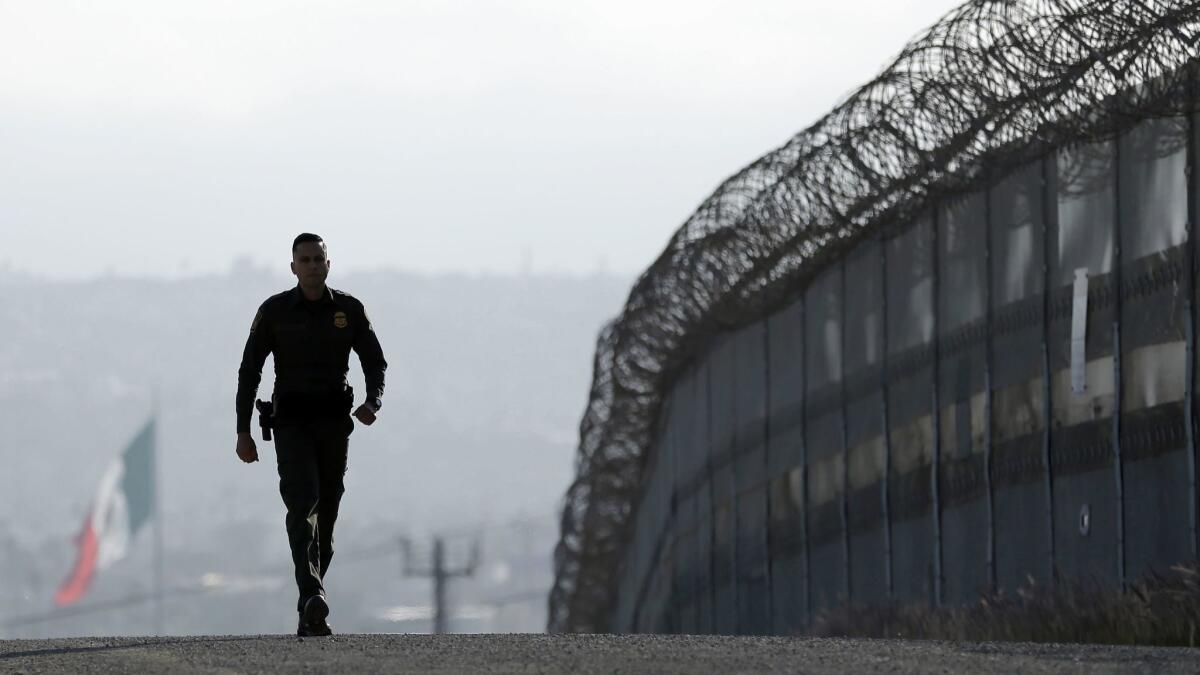 A Border Patrol agent near the secondary fence separating Tijuana, background, and San Diego.