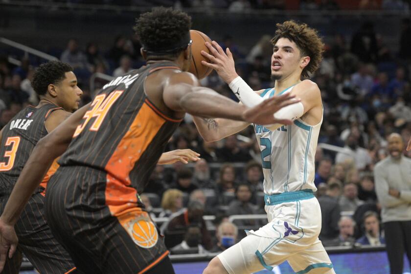 Charlotte Hornets guard LaMelo Ball (2) drives to the basket between Orlando Magic forward Chuma Okeke (3) and center Wendell Carter Jr. (34) during the first half of an NBA basketball game, Wednesday, Nov. 24, 2021, in Orlando, Fla. (AP Photo/Phelan M. Ebenhack)