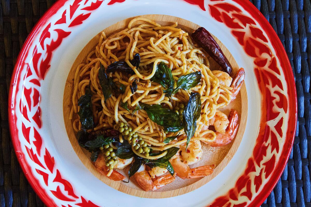 An overhead photo of tom yum spaghetti, topped with fried basil, on a red and white tray at Crazy Thai Burger in Koreatown.