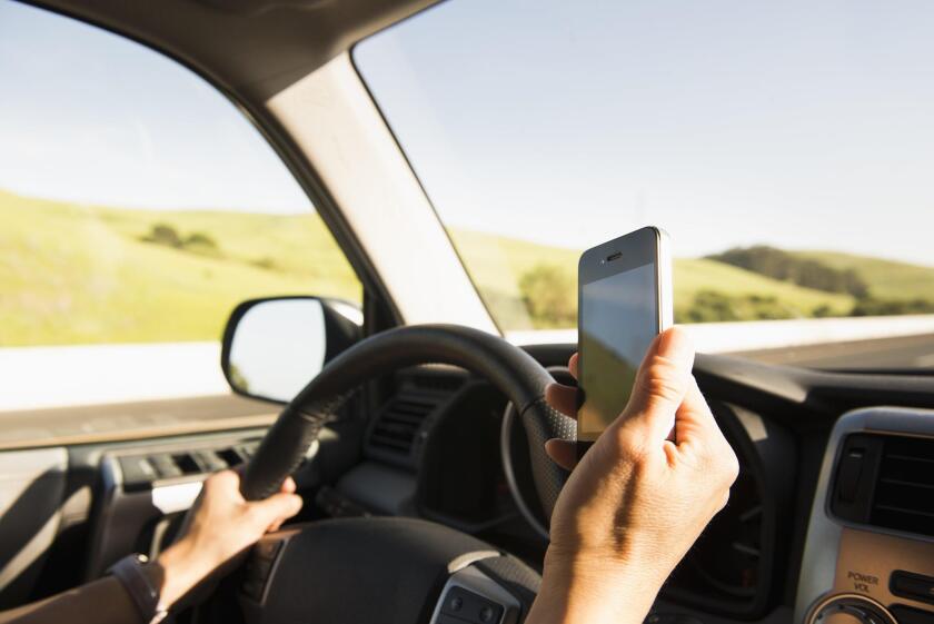 Woman driving and using cell phone