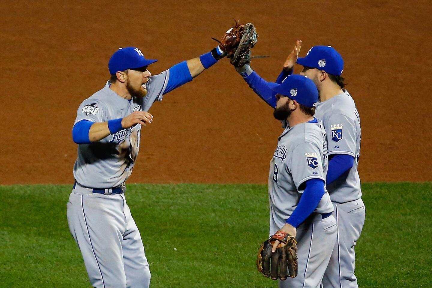 Mike Moustakas #8, Ben Zobrist #18 and Eric Hosmer #35 of the Kansas City Royals celebrate after defeating the New York Mets by a score of 5-3 to win Game Four of the 2015 World Series at Citi Field.