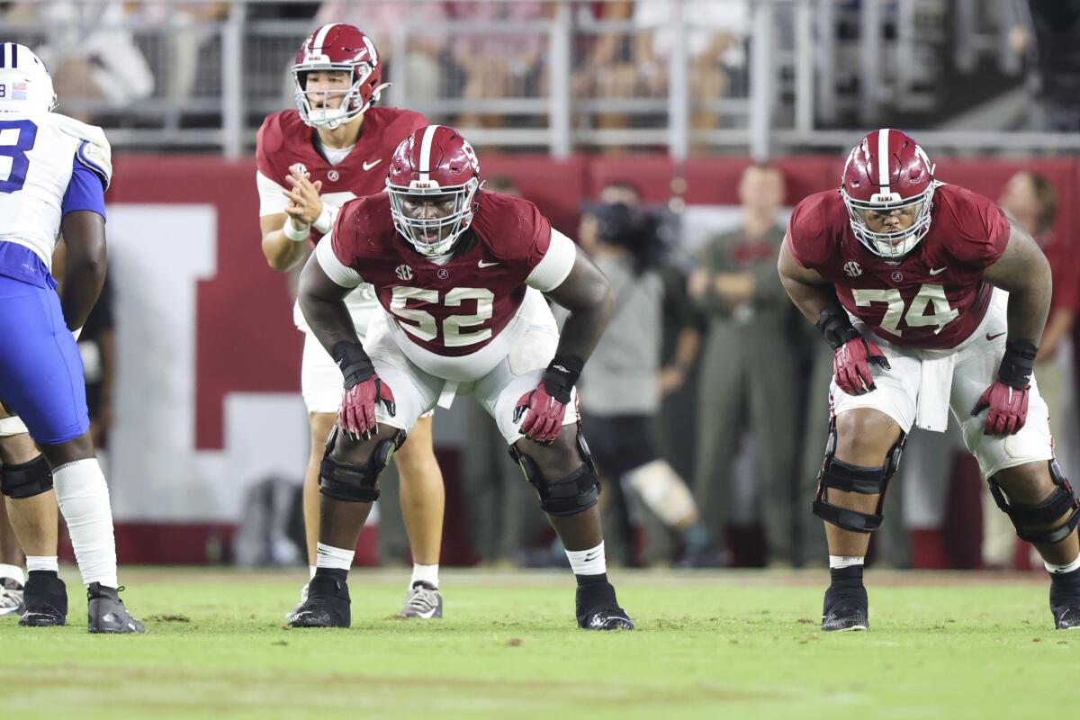 Alabama offensive lineman Tyler Booker and his teammates lean forward at the line of scrimmage