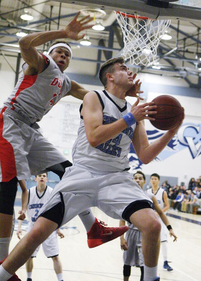 Crescenta Valley's Eric Patten hangs in the air to shoot on the opposite side of the basket to get around the defense of Pasadena's Tyrek Adams in a Pacific League boys basketball game at Crescenta Valley High School on Thursday, February 6, 2014.