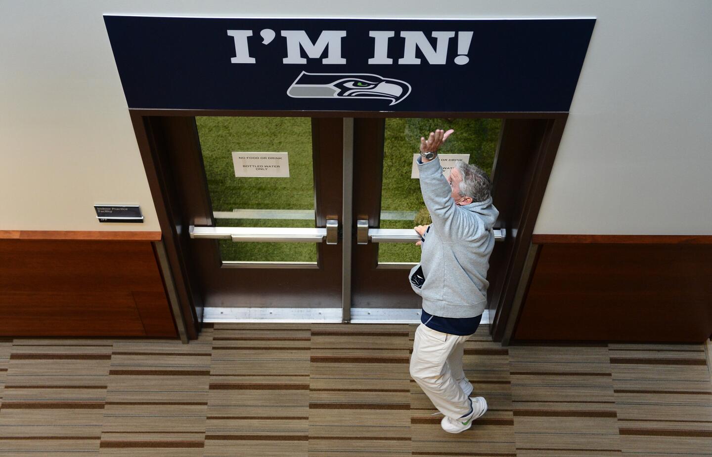 As a ritual Seahawks head coach Pete Carroll jumps to touch the sign before entering the practice facility in Seattle.