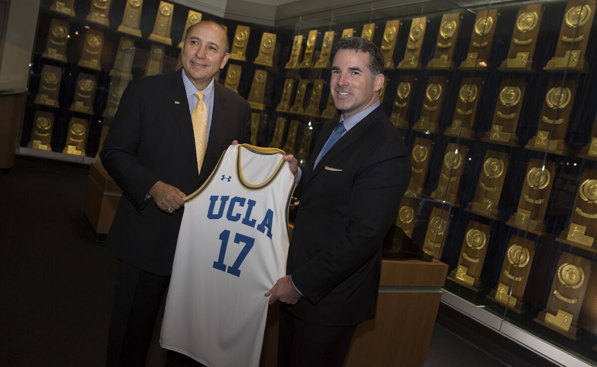 UCLA athletic director Dan Guerrero and Under Armour's Kevin Plank with a UCLA jersey.