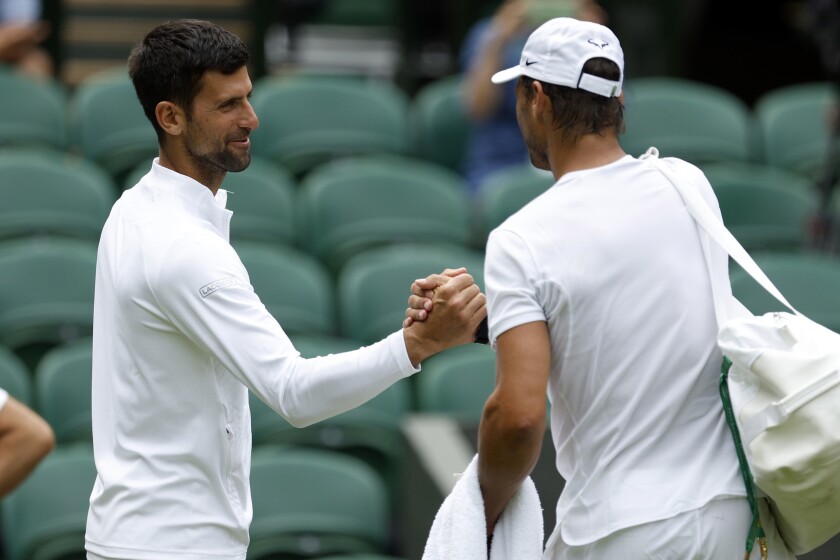 Spain's Rafael Nadal, right, greets Serbia's Novak Djokovic during a practice session on on Center Court ahead of the 2022 Wimbledon Championship at the All England Lawn Tennis and Croquet Club, in London, Thursday, June 23, 2022. (Steven Paston/PA via AP)