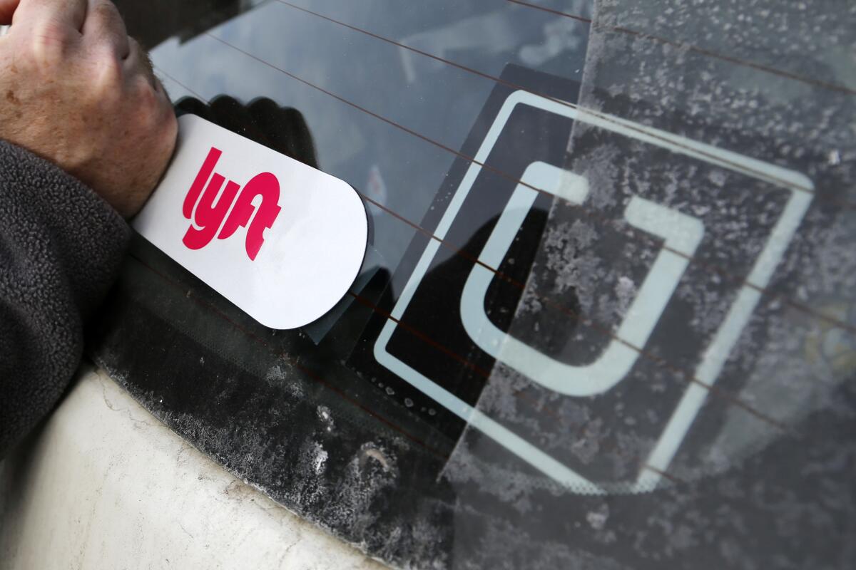 A Lyft logo is secured on a driver's car next to an Uber sticker in Pittsburgh. 