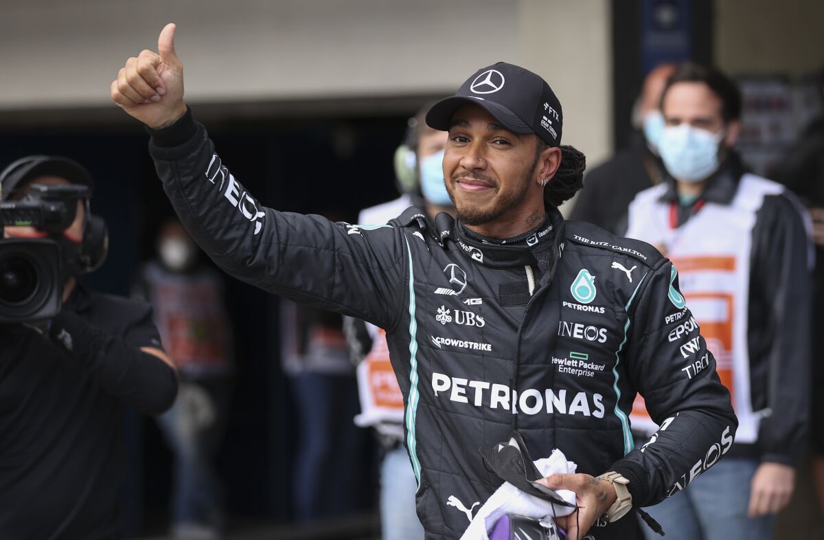 Mercedes driver Lewis Hamilton, of Britain, celebrates after winning the qualifying session for the Brazilian Formula One Grand Prix at the Interlagos race track in Sao Paulo, Brazil, Friday, Nov. 12, 2021. (Lars Baron/Pool via AP)