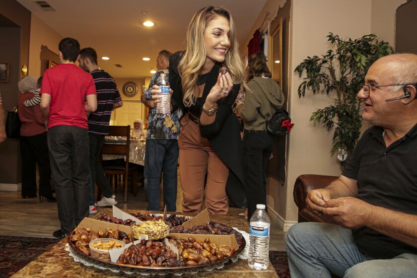 Montclair, CA - April 20: Aya Fejleh, left, and father Adnan Fejleh look for choicest piece of family grown Medjool date at a family gathering to end their daily Ramadan fast with a date at home on Tuesday, April 20, 2021 in Montclair, CA. (Irfan Khan / Los Angeles Times)