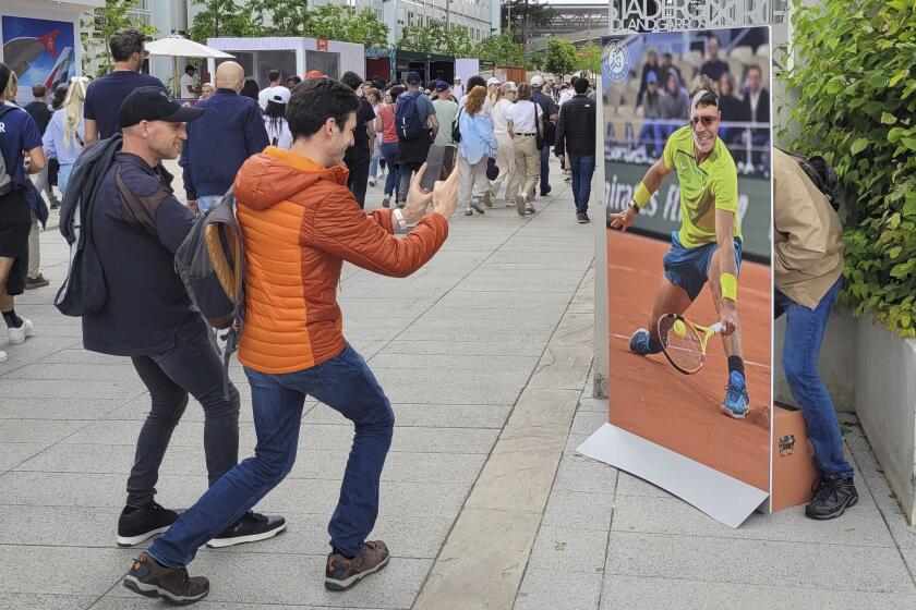 Un aficionado francés posa con una fotografía de tamaño real de Rafael Nadal junto al estadio central antes del Abierto de Francia el martes 21 de mayo del 2024. (AP Foto/Tom Nouvian)