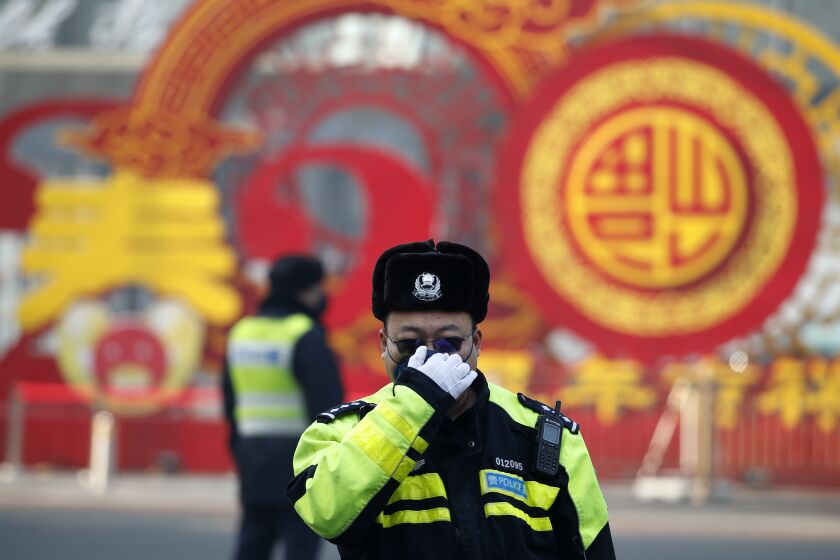 A traffic policeman adjusts his mask on a street in Beijing, Sunday, Feb. 9, 2020. China's coronavirus death toll on Sunday have surpassed the number of fatalities in the 2002-2003 SARS epidemic, but fewer new cases were reported in a possible sign its spread may be slowing as other nations step up efforts to block the disease. (AP Photo/Andy Wong)