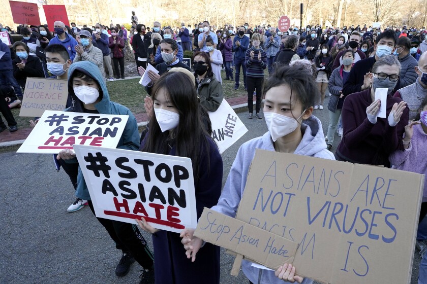 Protesters carry signs reading 'Stop Asian Hate' and 'Asians are not viruses. Racism is.'