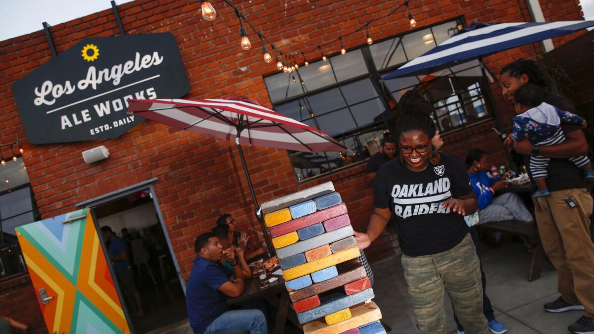 Sade Cooper works on an oversized Jenga game on the patio of Los Angeles Ale Works.