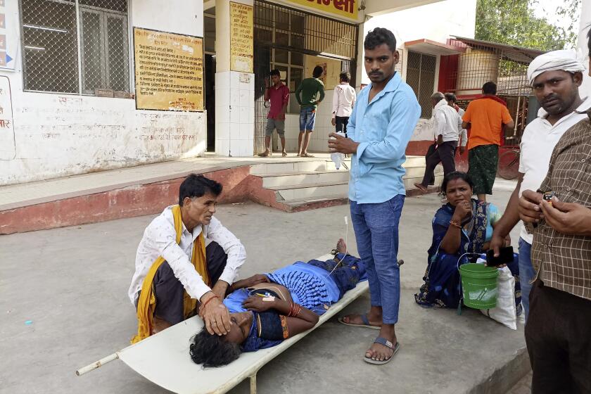Relatives attend to a patient lying on a stretcher in the premises of a hospital in Ballia district, in northern Uttar Pradesh state, India, Sunday, June 18, 2023. Swaths of two of India's most populous states are under a grip of sever heat leaving dozens of people dead in several days as authorities issue a warning to residents over 60 and others with ailments to stay indoors during the daytime. (AP Photo)