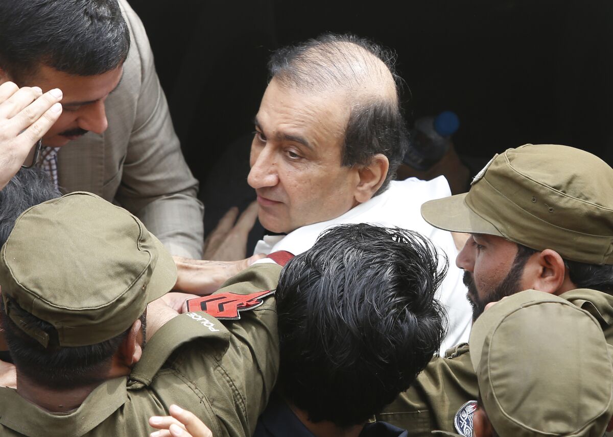 Pakistani police officers escort Mir Shakilur Rehman owner of Jang Group of Newspapers to an anti-graft court in Lahore, Pakistan, Friday, March 13, 2020. Pakistan's anti-graft body Thursday ordered the arrest of the owner and editor-in-chief of Pakistan's largest independent group of newspapers and TV stations in a decades-old case related to allegations of tax evasion in a real estate purchase. (AP Photo/K.M. Chaudhry)