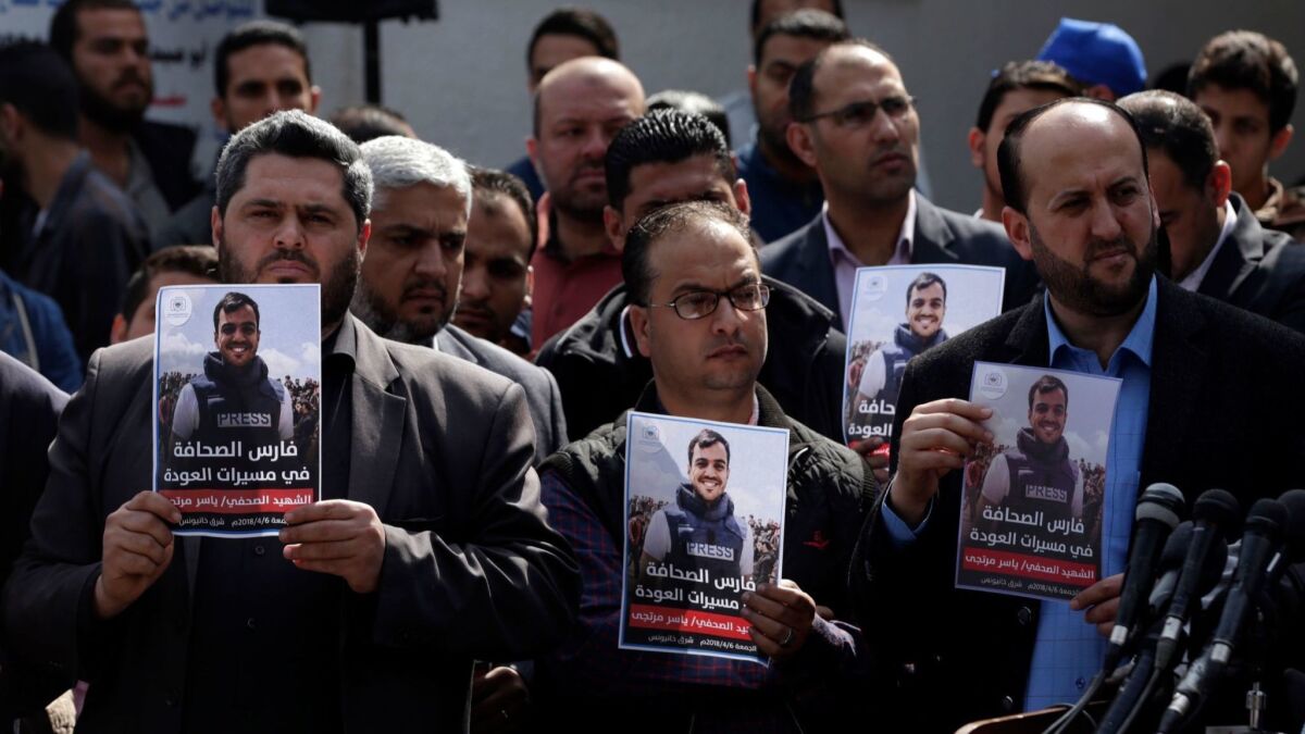Palestinian journalists carry a portrait of journalist Yasser Murtaja, during his funeral in Gaza City on April 7, 2018.