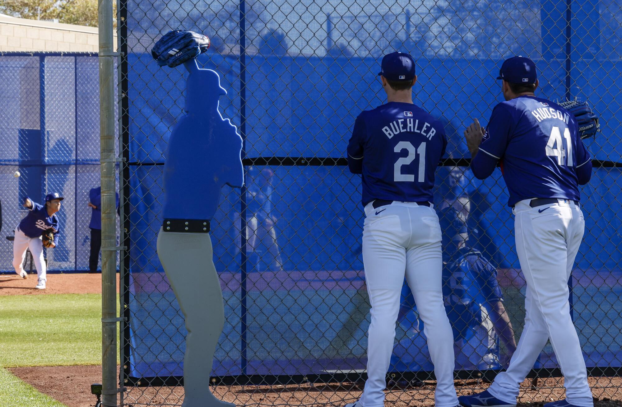 Pitchers Walker Buehler and Daniel Hudson look on as pitcher Yoshinobu Yamamoto, left, delivers a pitch