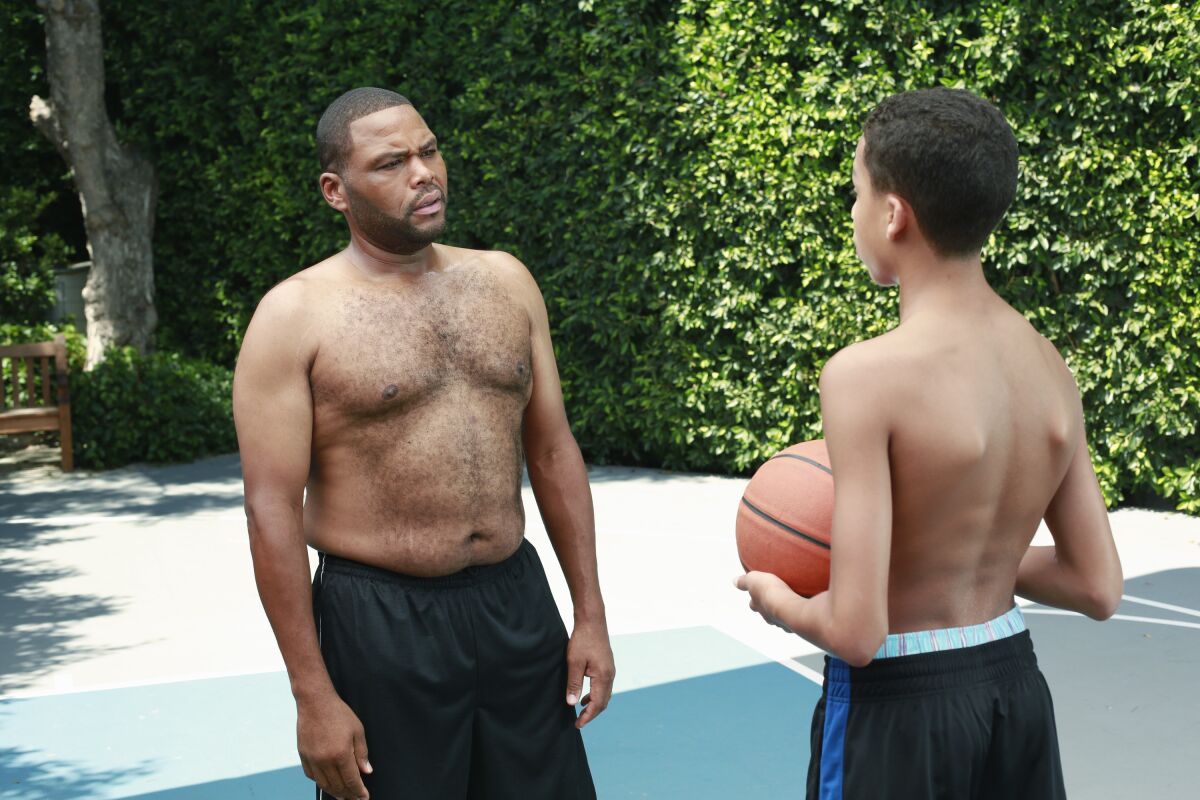 A father and son shirtless on a basketball court.