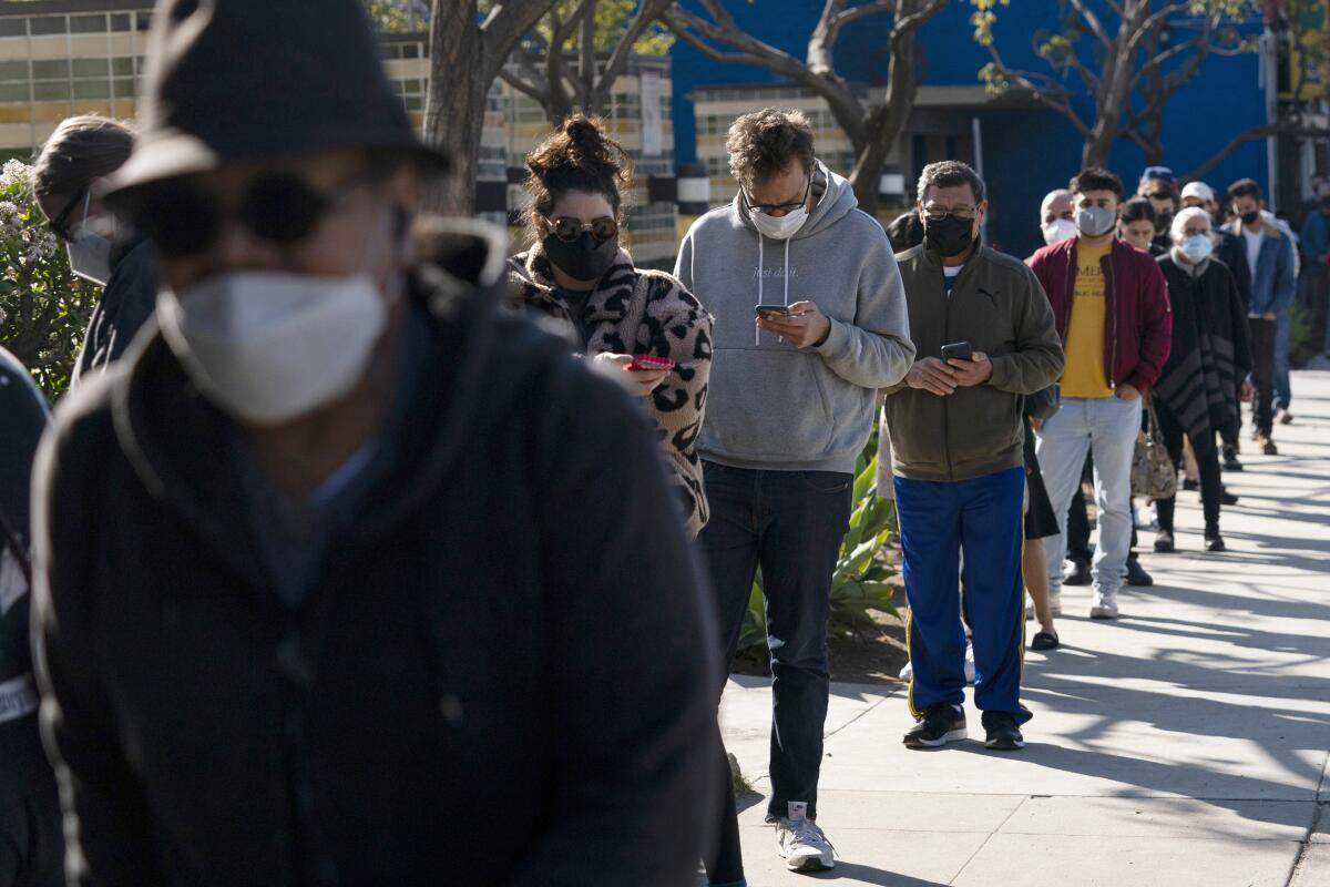 People wait in line wearing masks.