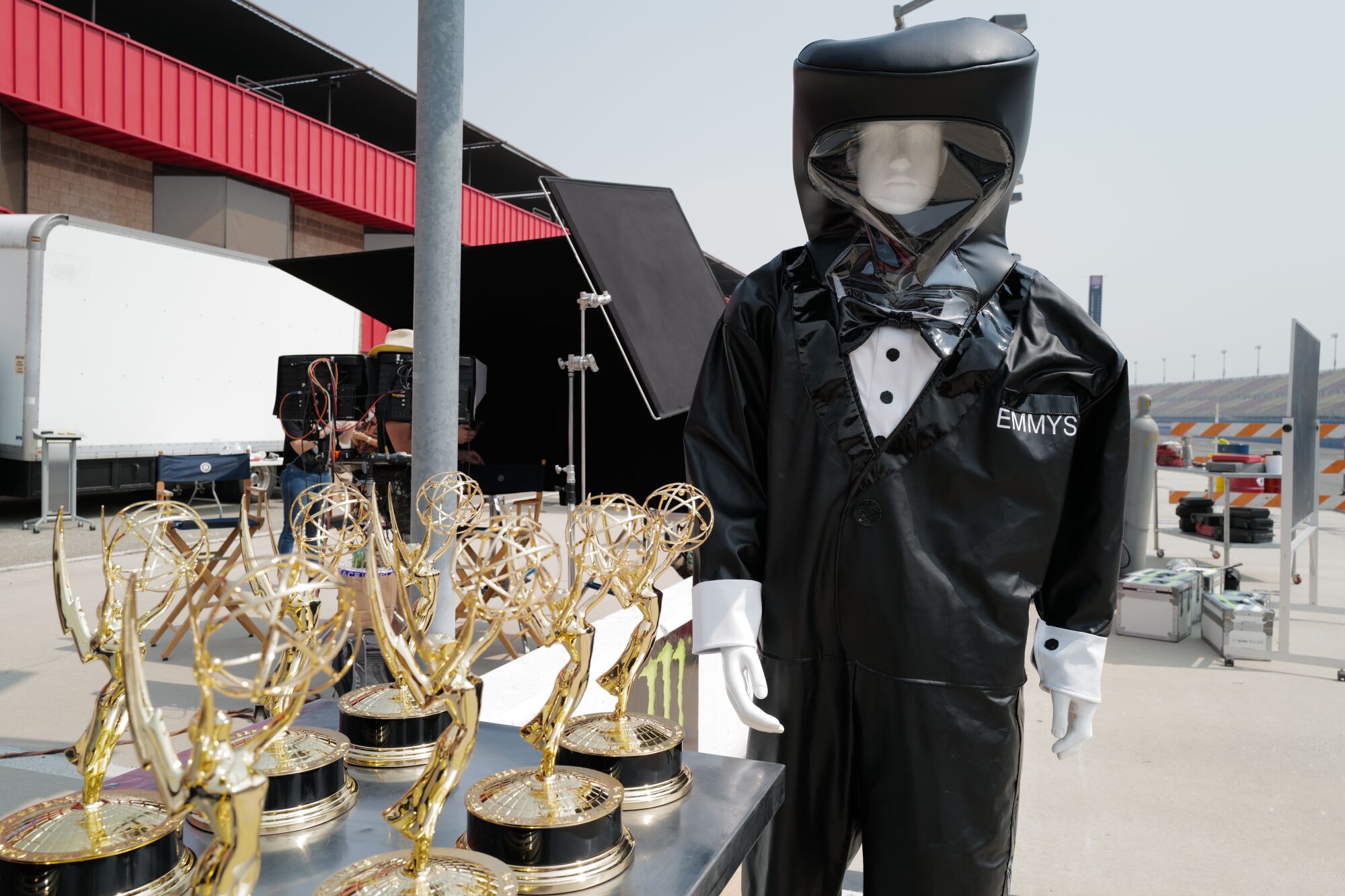 A mannequin in a hazmat tuxedo suit stands next to the Emmy statuettes 