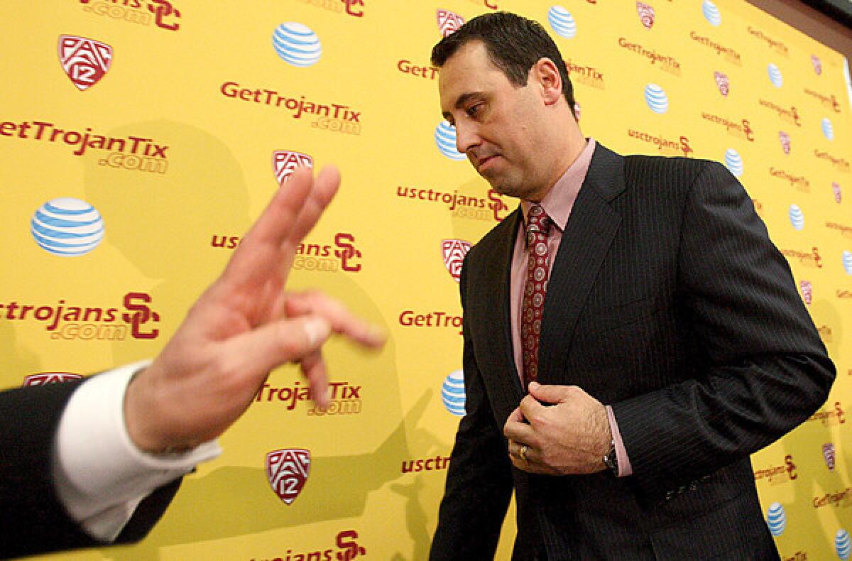 Steve Sarkisian leaves the stage after his introduction as USC's new football coach while university President C.L. Max Nikias flashes the victory sign.