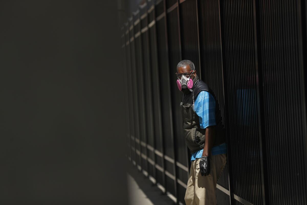 A man in Detroit wears a protective mask while waiting for a bus. Scientists would like to know more about which public health strategies are most effective at preventing the coronavirus from spreading.