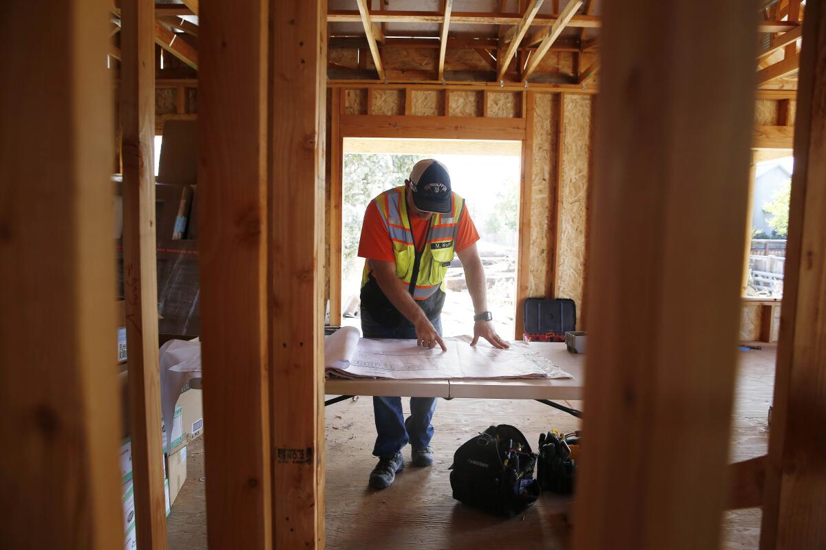 A worker inspects plans inside a partially constructed accessory dwelling unit in Santa Rosa
