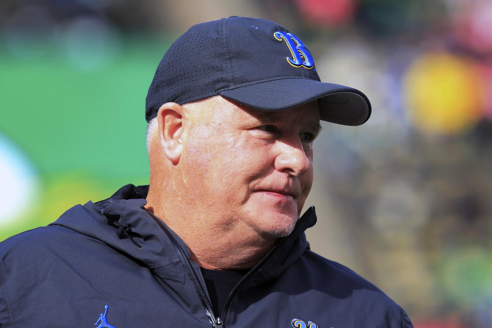 UCLA football coach Chip Kelly stands on the field before a game.