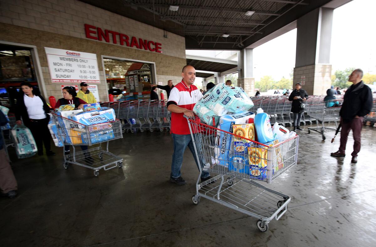 A shopper is among the first to exit Costco in Burbank after hundreds of customers lined up before doors opened, most looking for water, toilet paper, paper towels and cleaning supplies on Friday. Water and other necessities were out of stock within 20 minutes after the store opened.