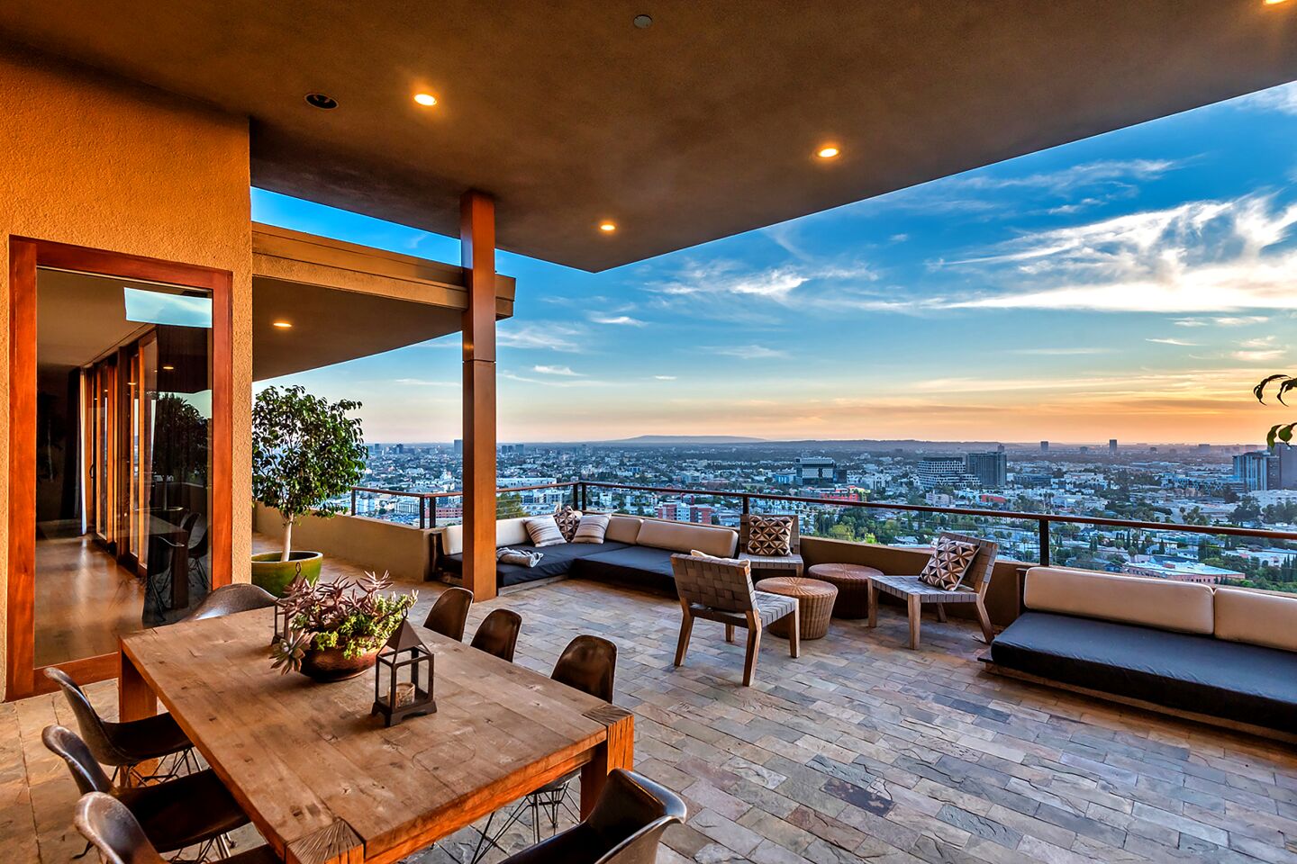 A spacious balcony has outdoor seating, a dining area and a view of the city.