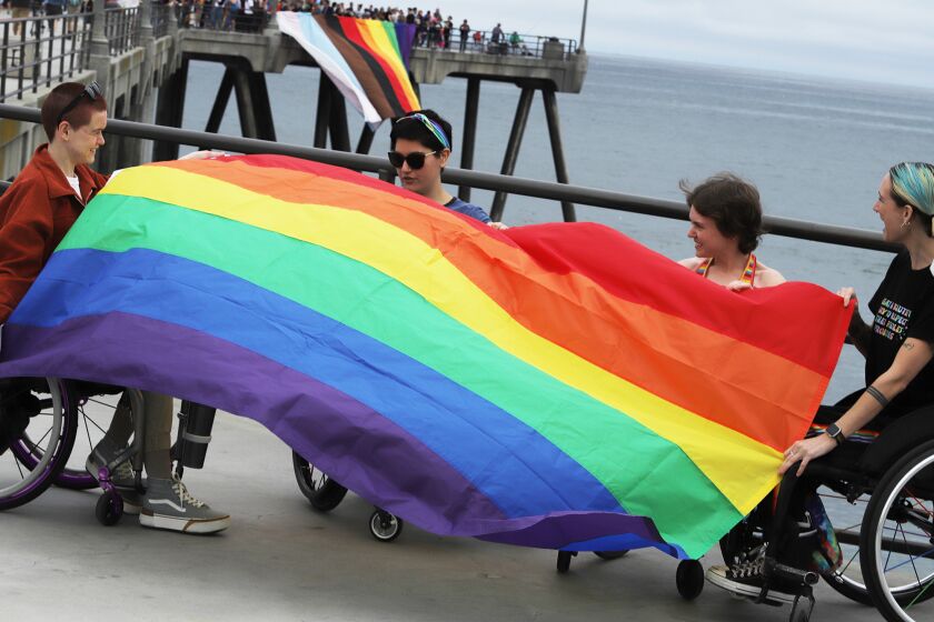 A group from "wheelie Queer of OC" hold their own pride rainbow flag at end of Huntington Beach pier, as a giant rainbow Pride flag measuring 33 feet by 24 feet hangs from the side of Huntington Beach's pier during a LGBTQ demonstration in Huntington Beach on Sunday, May 21, 2023. (Photo by James Carbone)