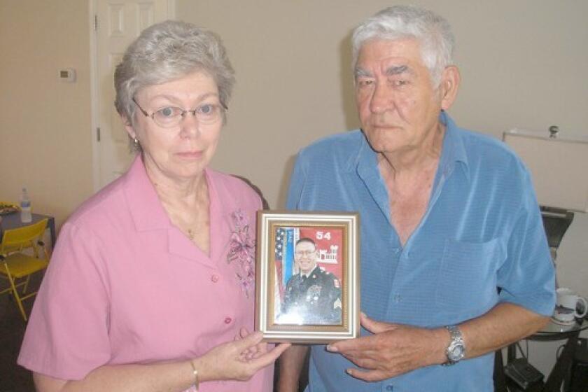 Wilburn and Elizabeth Russell hold a picture of their son, Army Sgt. John Russell, who is accused of killing five U.S. personnel in Iraq. He is being held in Kuwait and could face execution if convicted.