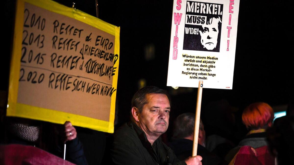 People hold banners reading "Merkel has to go," and "2010 Saves the Euro, 2013 Saves Greece, 2015 Saves the refugees - 2020 Save yourself who can" during a protest against German Chancellor Angela Merkel in Chemnitz, Germany, on Nov. 16.