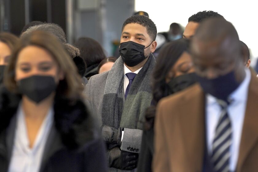 A man wearing a black face mask stands in a crowd