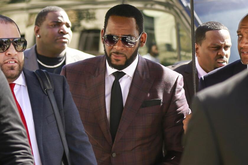 FILE - In this June 26, 2019 file photo, R&B singer R. Kelly, center, arrives at the Leighton Criminal Court building for an arraignment on sex-related felonies in Chicago. Federal prosecutors announced charges Wednesday, Aug. 12, 2020, against three men accused of threatening and intimidating women who have accused Kelly of abuse, including one man suspected of setting fire to a vehicle in Florida. (AP Photo/Amr Alfiky, File)