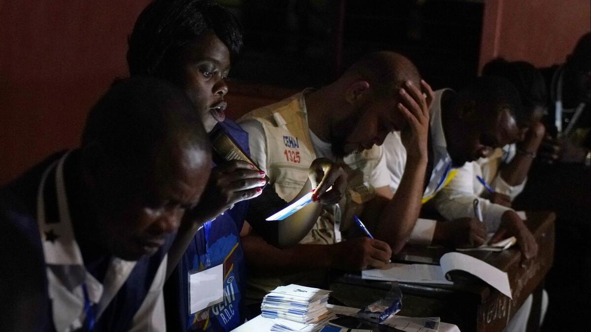 Electoral commission officials tally the presidential ballots in Kinshasa, Congo, on Sunday night.