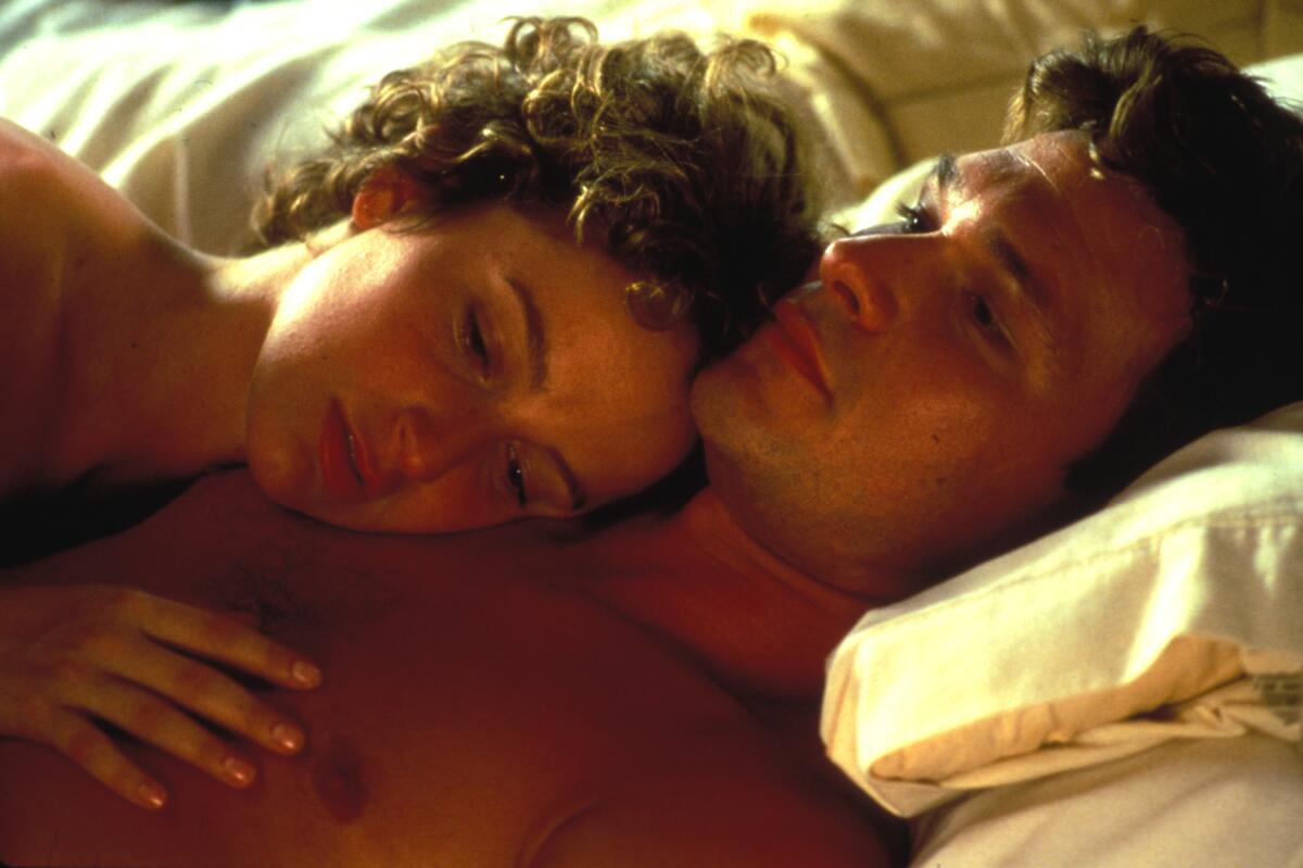 A woman rests on a man's chest in bed 