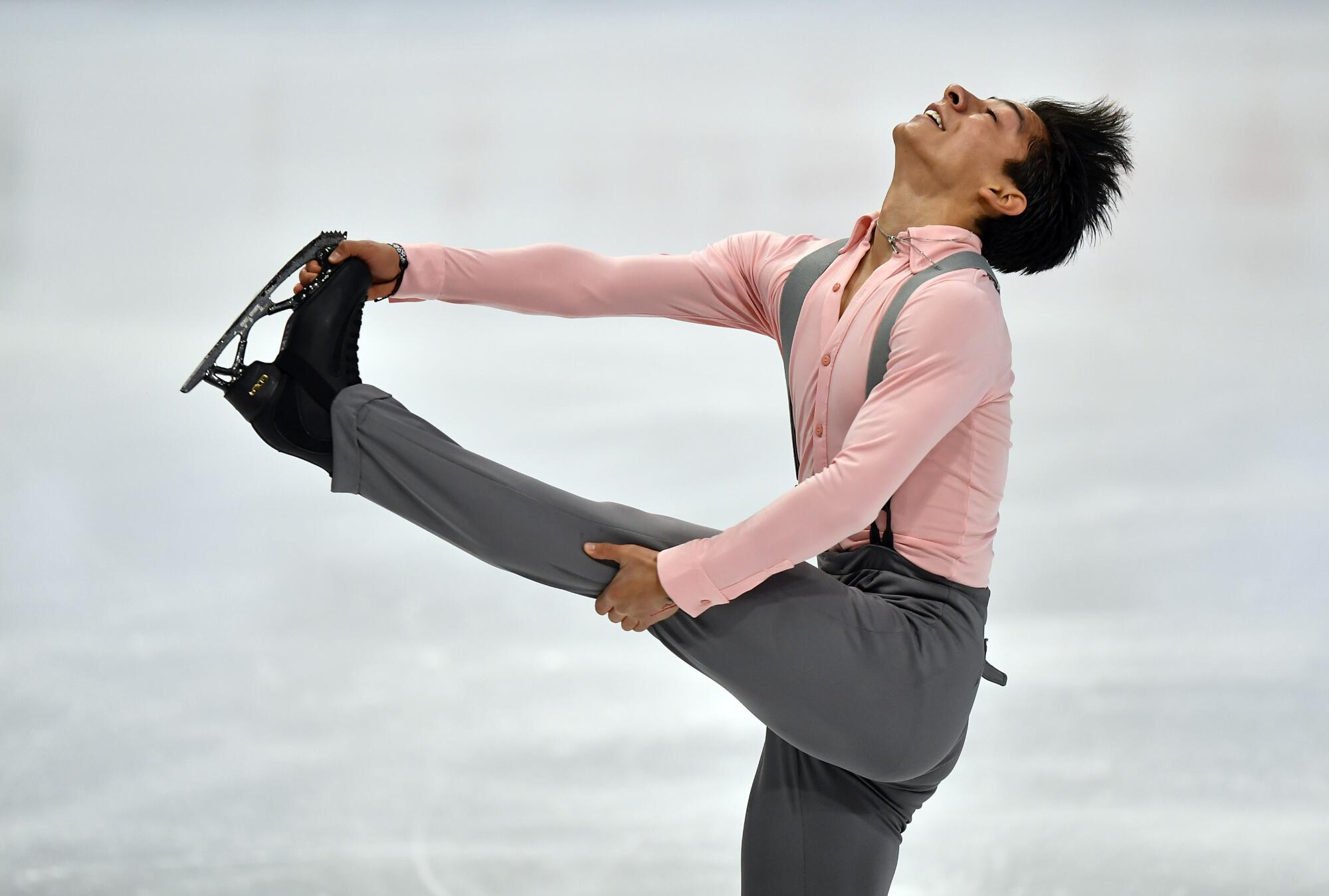 Donovan Carrillo lifts his left leg and holds his skate with his hand while skating at the world championships.