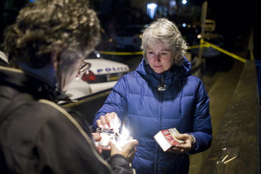 D.J. Thomson, right, and Joyce Levine light candles on Kennedy Street in downtown Juneau for Mayor Greg Fisk, who was found dead in his home this week.