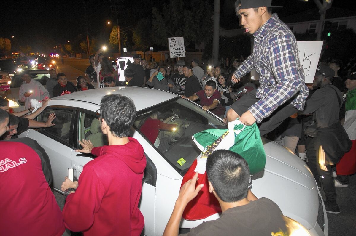 Protesters surround a car at the corner of Fairview Road and Fair Drive on Thursday following a Donald Trump rally at the Orange County fairgrounds.