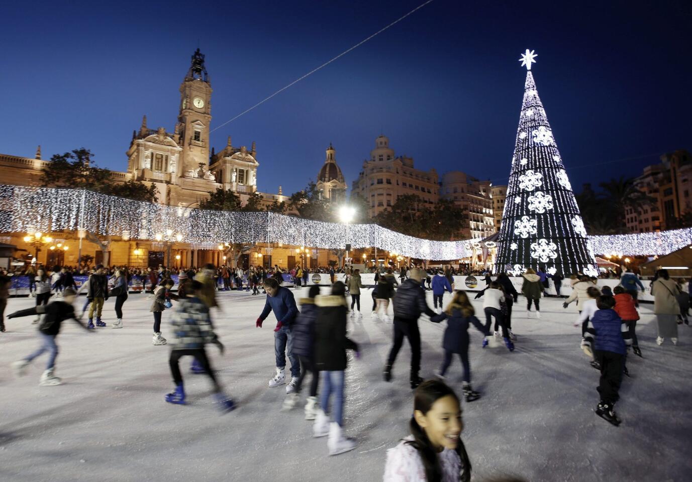 People enjoy an ice-skating rink at the Town Hall square in Valencia.
