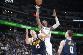 Brooklyn Nets forward Harry Giles III (14) goes up for a basket between Denver Nuggets center Nikola Jokic (15) and Denver Nuggets guard Christian Braun (0) in the second half of an NBA basketball game Thursday, Dec. 14, 2023, in Denver. (AP Photo/David Zalubowski)
