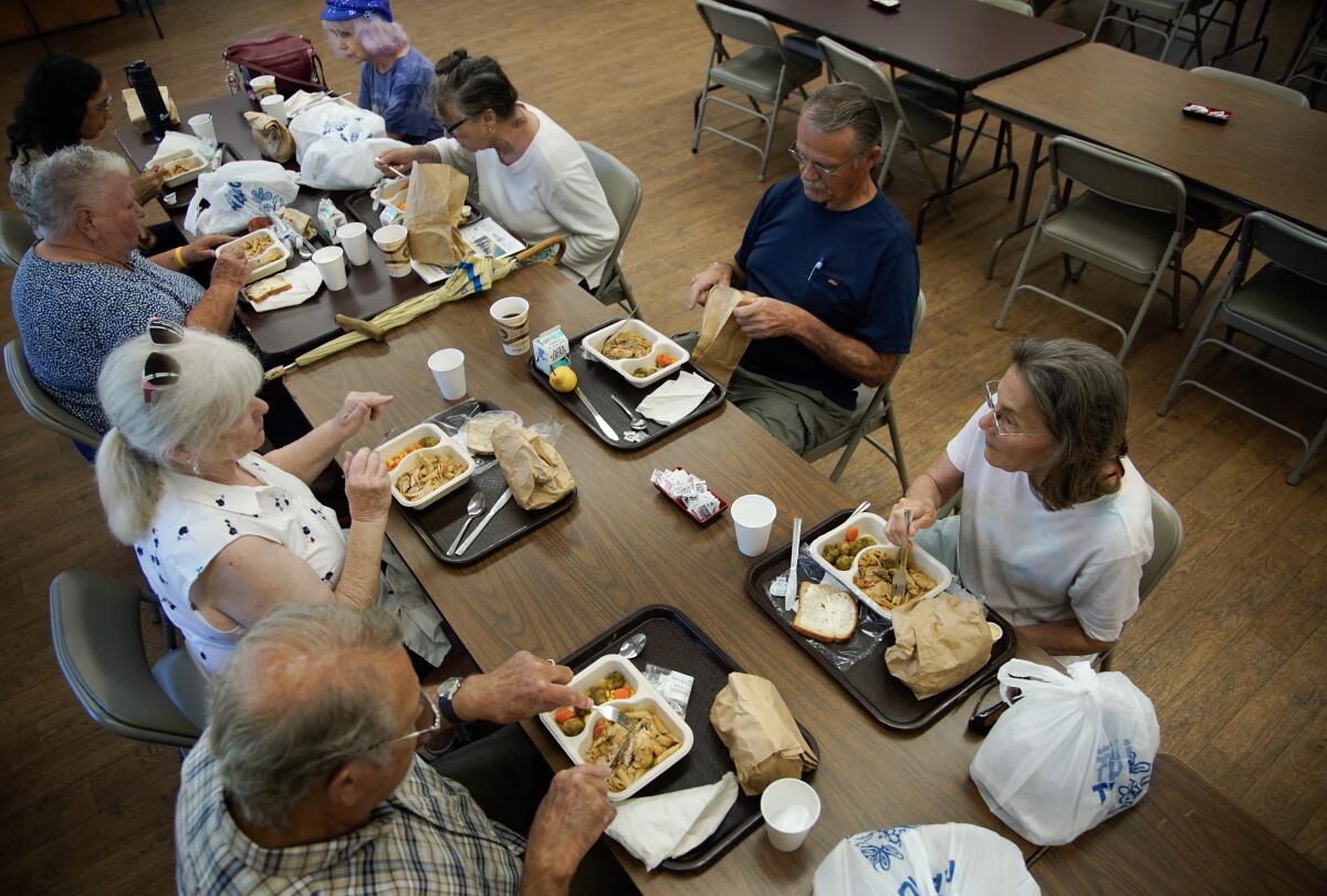 older adults sit at a cafeteria table while eating lunch