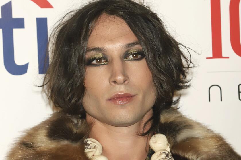 A person with sparkling eye make up and dark hair wearing a fur coat