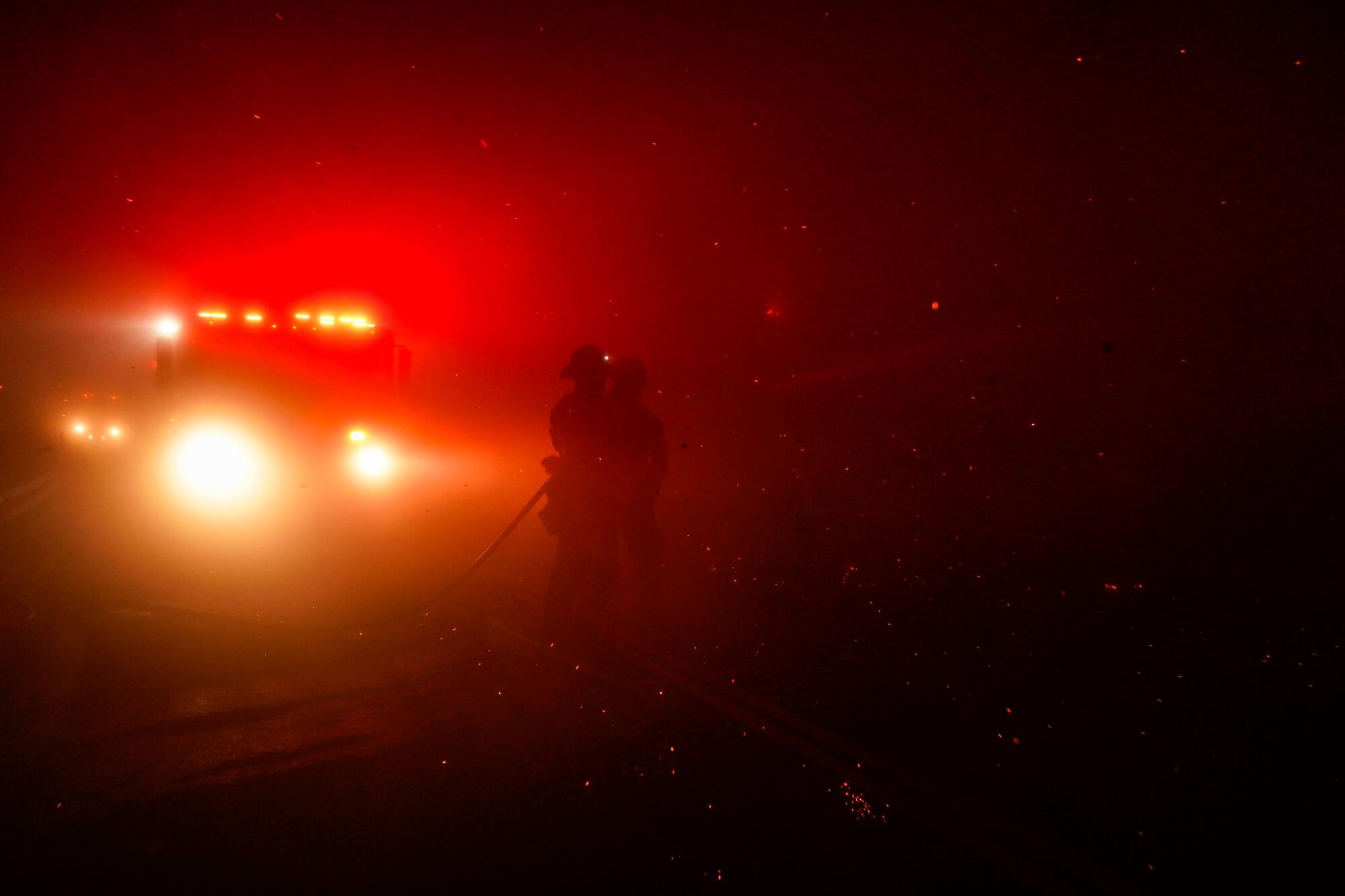 Firefighters at night in front of lights from a fire engine