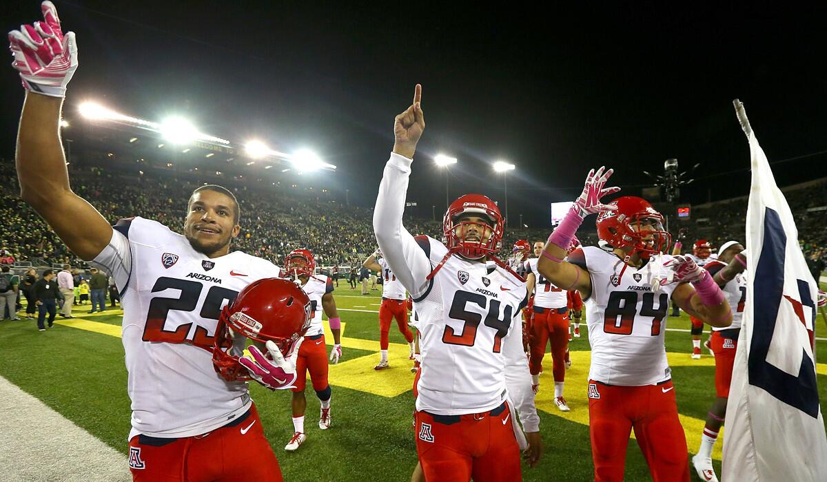 Arizona players Jarvis McCall Jr. (29), Jose Romero (54) and Abraham Medivil (84) celebrate after their 31-24 victory at Oregon Oct. 2.