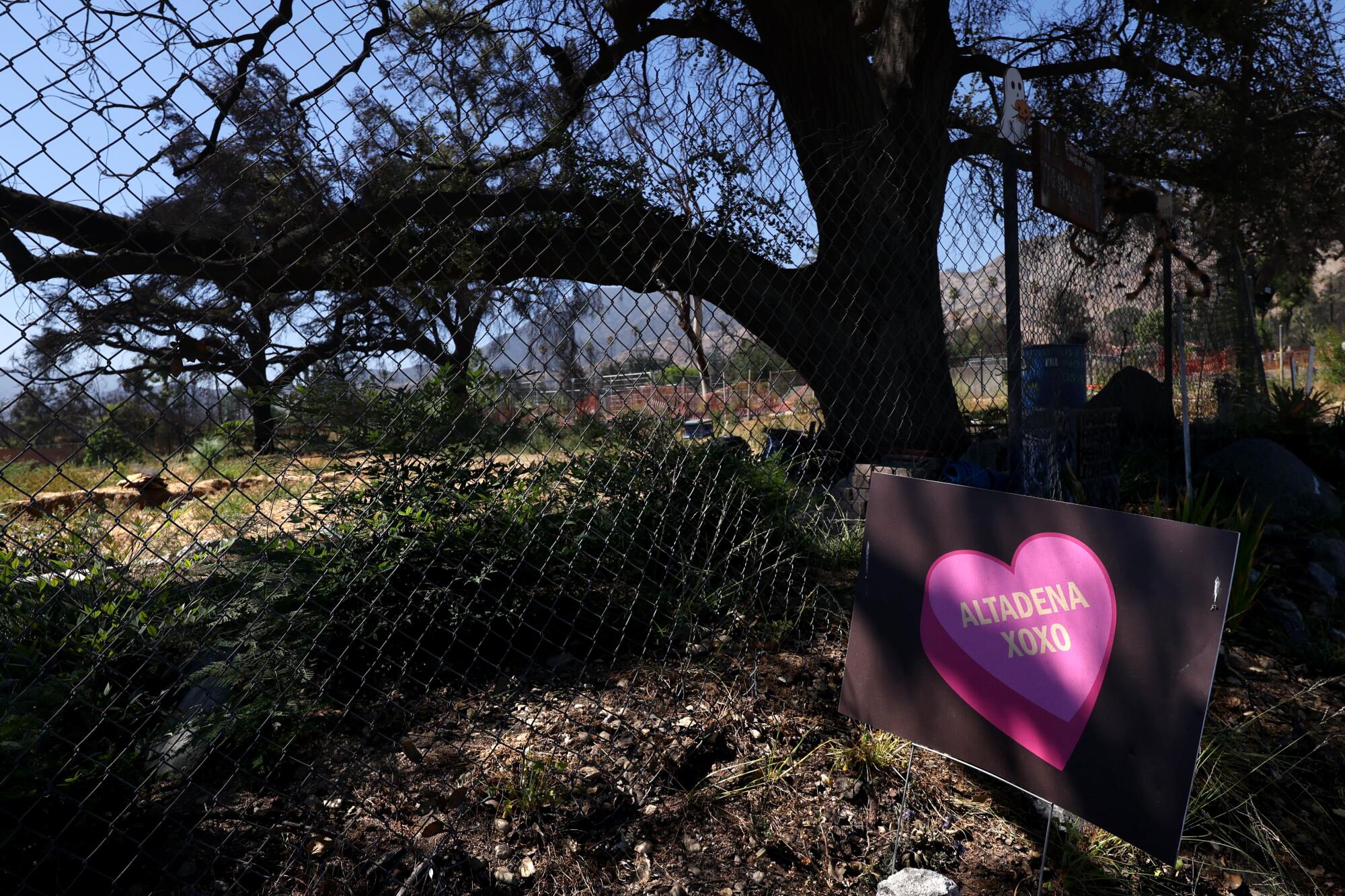 A sign offering "hugs and kisses" to Altadena rests in the front yard of a home that was destroyed in the Eaton fire.